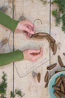 Attach the pine cones to the hanger frame using the copper thread