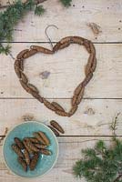 Pine cones secured to a coat hanger in the shape of a heart
