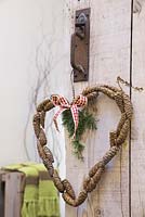 Pine cones secured to a coat hanger in the shape of a heart
