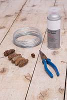 Materials required are Pine cones, pliers, wire and silver spray paint