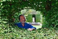 Patrice Taravella, owner of Le Prieuré Notre-Dame d'Orsan looks through a window clipped out of the hornbeam hedges
