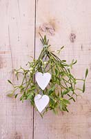 A bunch of mistletoe hanging on a door, with Clay hearts featuring textured imprints