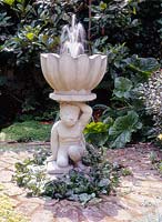 Chilstone fountain in shape of man carrying bowl surrounded by bricks with ajuga and soleirolia. July