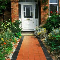 City housefront with tiled path to front door, borders with tropaeolum and sisyrinchium. Garden of Laura and Godfrey Issacs
