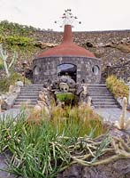 El Jardin cactus. Lanzarote, Shop built from volcanic rock with wind mobile on roof