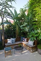 Outdoor living area with bench seat in small courtyard garden showing Himalayan pavers, Strelitzia Bird of Paradise and Bambusa textilis gracilis 'Slender Weaver' bamboo along fencing