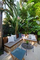 Outdoor living area with bench seat in small courtyard garden showing Himalayan pavers, Strelitzia Bird of Paradise and Bambusa textilis gracilis 'Slender Weaver' bamboo along fencing