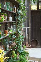 View of wooden shelves with artefacts and old tools and raised bed, Lucille Lewins, small office court yard garden in Chiltern street studios, London. Designed by Adam Woolcott and Jonathan Smith 