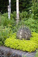 Contemporary stone sculpture 'Spike' by artist Jill Sutcliffe amongst foliage