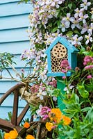 Wildlife gardening - early summer garden with home made bug box placed on side of garden shed.