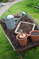 Using garden compost for seed sowing - wheel barrow with well rotted garden compost, home made sieve, terracotta pots and traditional watering can.