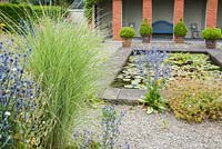 The pond garden has a still, reflecting pool at its centre full of water lilies, with silver and pastel planting including miscanthus, Eryngium planum 'Blaukappe' in mirror borders either side and pots of box at one end. The Bay Garden, Camolin, Co Wexford, Ireland