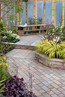 Seating area and paving path with raised borders in the 'Garden for All Ages' at BBC Gardener's World Live 2015