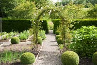 Rose arch in the centre of the formal vegetable garden with box spheres on the corners of the beds. Upper Tan House, Stansbatch, Herefordshire, UK