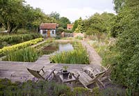 Natural Swimming Pool with wooden reclining chairs and borders of rosmarinus officinalis, alchemilla mollis. Snares Hill Cottage, Essex
