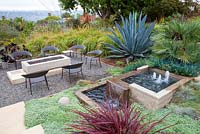 Outside seating area with gas fire pit and concrete contemporary water feature. Debora Carl's garden, Encinitas, California, USA. August.
