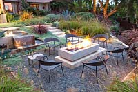 View of fire pit alight and outside seating area at night. Debora Carl's garden, Encinitas, California, USA. August.