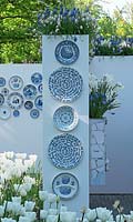 All kinds of Delfts Blue designed patterns on plates hanging at a wall. White and blue Muscari, white Tulips and Narcissus. Inspiration garden: Delfts Blue.