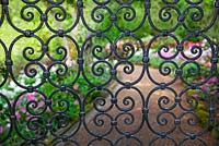 View through wrought iron gate leading to garden - Pashley Manor Gardens, Kent, UK