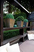 Geometric wooden loggia seating area with cushions, ornaments and containers.

