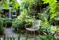 Wide view or urban back garden with chair, angel sculpture and raised flower beds