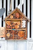 Insect hotel on the white painted wall of a wooden garden shed