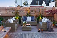 Outside seating area at dusk with lit candles on a London roof terrace. April. 