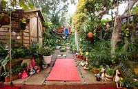 Wide view of inner city garden with begonias, ferns and palms features colourful eclectic retro pieces sourced from local markets. 