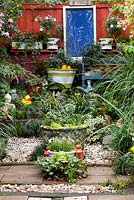 A collection of retro cement pots, quirky garden ornaments and a blue framed garden decoration focal point.