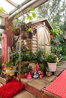 A collection of quirky pink coloured decorative objects in front of a small timber garden shed.