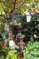 A collection of quirky statues, pots and an old blue painted birdcage, in amongst Cloeus, Lamium, Pelargonium and succulents.