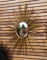 French sixties starburst mirror on wooden panelling. Ben De Lisi House and Garden, London