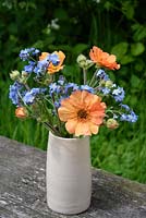 Orange Geum with forget-me-nots in small pottery vase