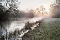 Mist rises at dawn from the River Lambourn that runs through the grounds of Welford Park, Newbury, Berks, UK