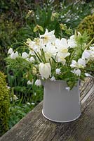 White spring floral arrangement in enamel jug including Narcissus, Fritillaria meleagris 'Alba, Hyacinthoides hispanica 'Alba', Leucojum vernum and muscari