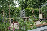 Detail of 'A Summer Retreat', designed by Amanda Waring and Laura Arison, showing a paddle stone wall of black quartz, and a spiral sculpture and water feature by Giles Rayner. Other features include a bespoke Summerhouse and handcrafted wooden seating. Planting includes silver birch, hornbeam, pittosporum, agastache, dahlia, artemesia, echinace, foxgloves and verbena bonariensis. Hampton Court Flower Show, July 2016.