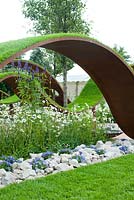 'The World Vision Garden', designed by John Warland, waves of turf. Planting consists mainly of Hornbeam hedging, Ornamental Pear trees and meadow areas of Ox-eye daisies. Hampton Court Flower Show, July 2016.