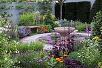 The St John's Hospice Garden, The Modern Apothecary. Oak bench and water basin in herb garden with circular cobble stone path. RHS Chelsea Flower Show 2016 - Designer: Jekka McVicar, Sponsor: St John's Hospice