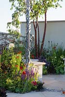 Hand forged metal pergola by Dragonswood Forge, Prunus serrula var. tibetica in corner surrounded by colourful planting including Salvia,  Helenium 'Moerheim Beauty' and Agapanthus 'White Heaven' - New Horizons, RHS Hampton Court Palace Flower Show 2016