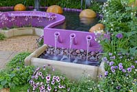 Water cascades from violet pool in Papworth Trust - Together We Can with acoustic effects generated by water merimba. The RHS Chelsea Flower Show 2016. Designer: Peter Eustance MSGD, Sponsor: Papworth Trust. SILVER GILT