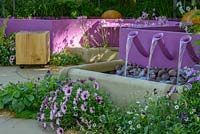 Water cascades from violet pool in Papworth Trust - Together We Can with acustic effects generated by water merimba. RHS Chelsea Flower Show 2016. Sponsor: Papworth Trust. Designer: Peter Eustance MSGD. SILVER GILT