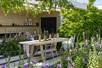 An outside-room in The LG Smart Garden, a Scandinavian lifestyle garden inspired by moden technology and softened by delicate pstel planting and framed by Wisteria 'Schowa Beni'. The RHS Chelsea Flower Show 2016 - Designer: Hay Joung Hwang - Sponsor: LG Electronics - SILVER-GILT