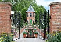 The Harrods British Eccentrics Garden. View through gates to the pool, house and borders. RHS Chelsea Flower Show 2016, Designer - Diarmuid Gavin.