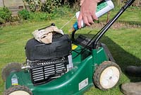 Four stroke petrol lawnmower, being filled with fresh engine oil, UK, March