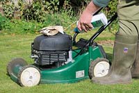 Four stroke petrol lawnmower, filling engine with fresh oil, UK, March