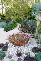 The Winton Beauty of Mathematics Garden, view of copper water feature, sand path and stones surrounded by Yucca rostrata, Dasylirion wheeleri, Echeveria 'Duchess of Nuremberg', tropical, Mediterranean plants. The RHS Chelsea Flower Show 2016, Designer: Nick Bailey, Sponsor: Winton