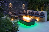 Secluded seating area with a dry stone slate wall and propane fire pit emitting green light