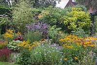 A mixed tropical style border of hot colours - August, Cheshire