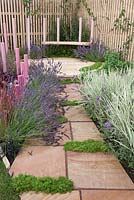 A natural stone slab path leading to a  seat attached to pink painted wooden posts.  Hidden Message, RHS Tatton Flower Show 2011, Cheshire