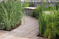 Grasses, bleached wooden decking and gabion seat. Garden: 'A Prison Garden For Rehabilitation' at RHS Tatton Park Flower Show 2012
